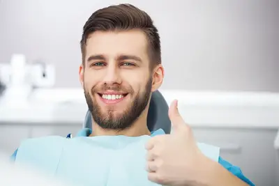 A man giving his thumbs up while sitting in a dental chair