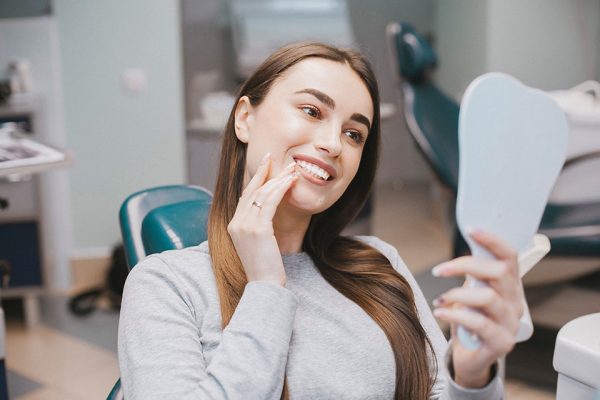 woman looking at her new smile at the dentist