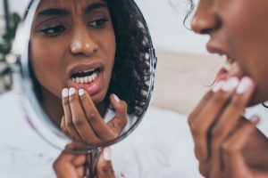 woman looking in a mirror at her teeth